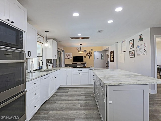 kitchen featuring stainless steel oven, white dishwasher, a sink, black microwave, and a peninsula