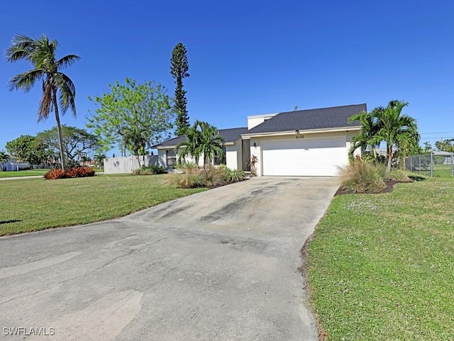 view of front facade with driveway, a garage, fence, and a front lawn