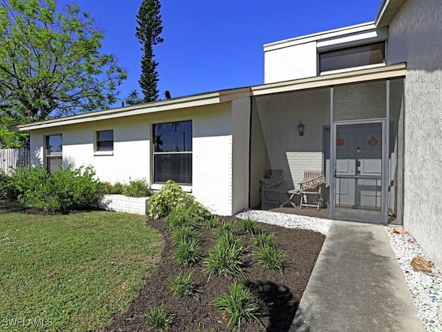 back of house with a sunroom, a lawn, and stucco siding