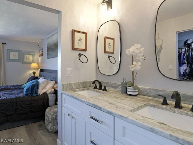 bathroom featuring wood finished floors, double vanity, a sink, and ensuite bathroom