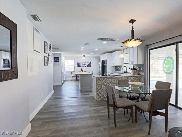 dining space featuring dark wood-style floors, visible vents, baseboards, and a wealth of natural light