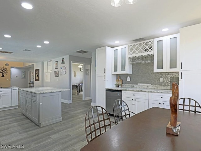 kitchen with white cabinets, a kitchen island, light wood-style flooring, and dishwashing machine