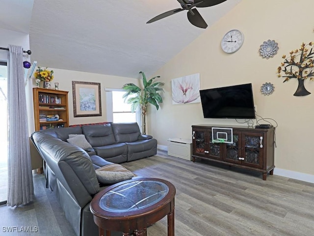 living room featuring lofted ceiling, a ceiling fan, baseboards, and wood finished floors