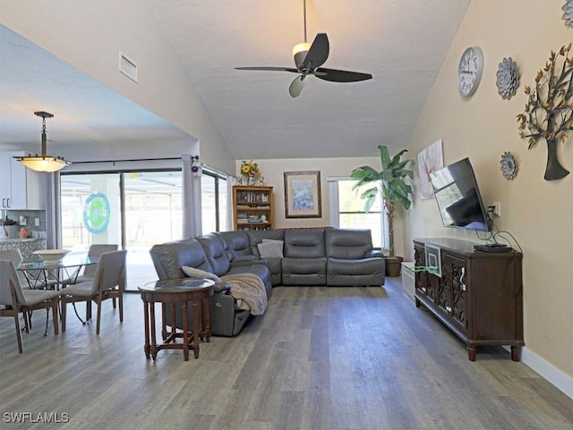 living room featuring lofted ceiling, visible vents, ceiling fan, wood finished floors, and baseboards