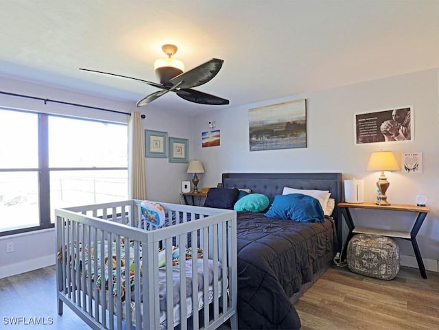 bedroom featuring ceiling fan, baseboards, and wood finished floors