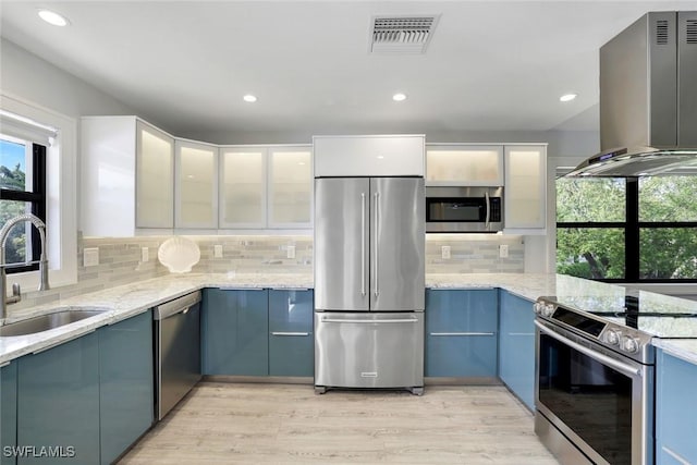 kitchen featuring plenty of natural light, visible vents, wall chimney exhaust hood, appliances with stainless steel finishes, and a sink