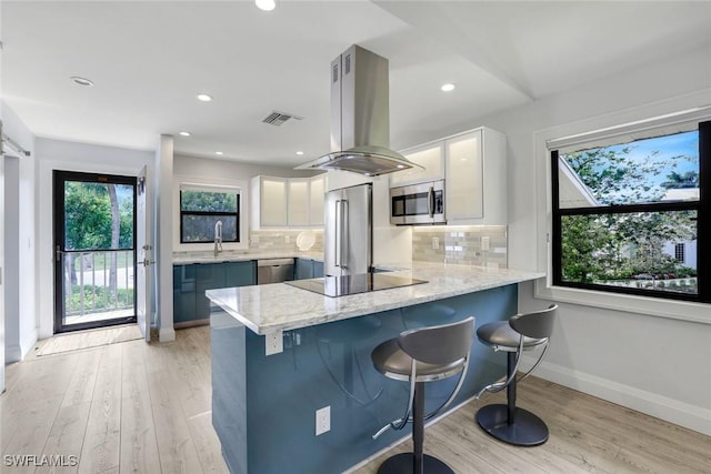 kitchen featuring stainless steel appliances, a peninsula, white cabinets, and island range hood