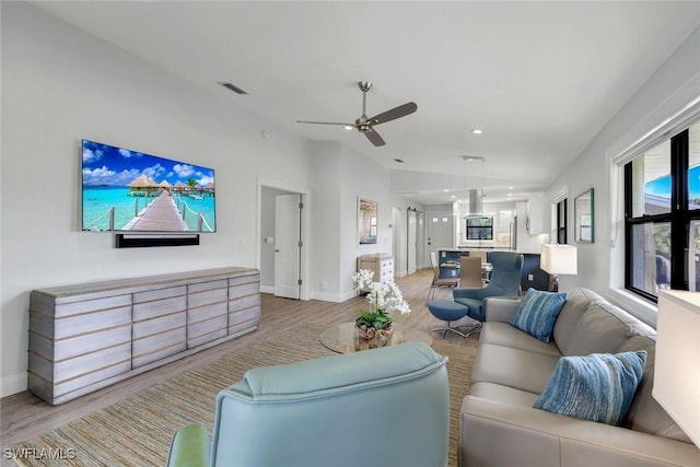 living area featuring baseboards, a ceiling fan, visible vents, and light wood-style floors