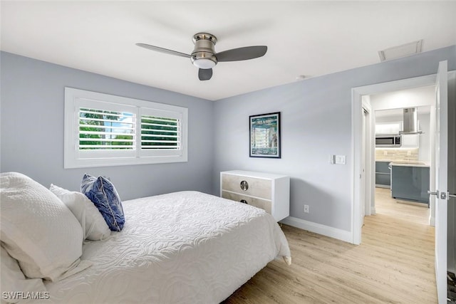 bedroom with a ceiling fan, light wood-style flooring, and baseboards