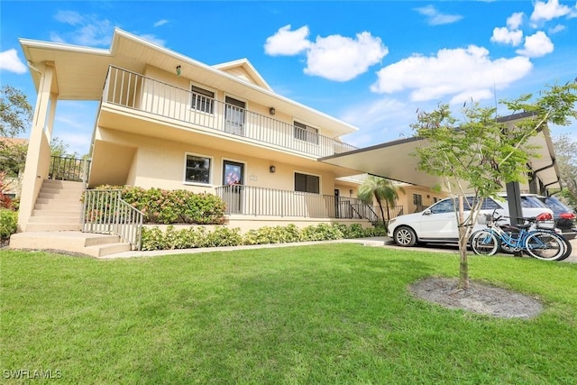 view of front of home featuring stairs, a front yard, a balcony, and stucco siding