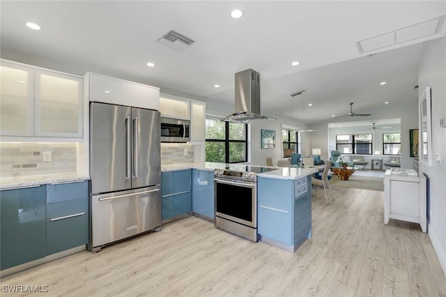 kitchen featuring visible vents, island range hood, modern cabinets, a peninsula, and stainless steel appliances