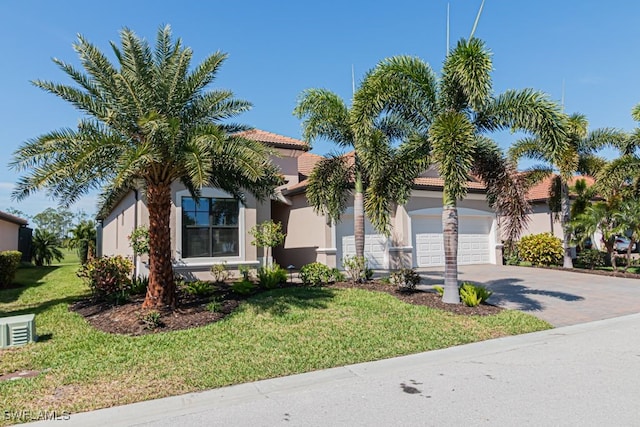 view of front facade featuring decorative driveway, a tile roof, stucco siding, an attached garage, and a front lawn