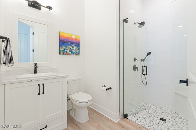 full bathroom featuring toilet, a stall shower, vanity, wood finished floors, and baseboards