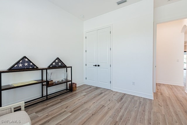 unfurnished bedroom with light wood-type flooring, visible vents, a closet, and lofted ceiling