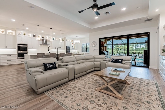 living room featuring a raised ceiling, visible vents, and a healthy amount of sunlight