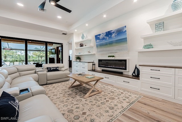 living room featuring ceiling fan, recessed lighting, visible vents, built in features, and light wood-type flooring