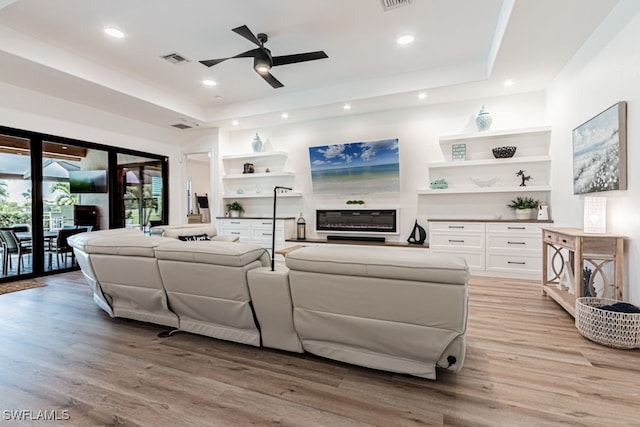 living room featuring light wood-style flooring, a raised ceiling, visible vents, and recessed lighting