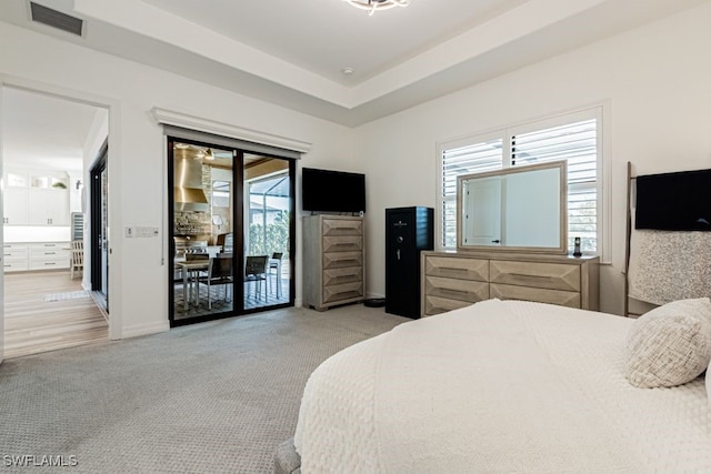 bedroom featuring a tray ceiling, visible vents, light carpet, access to outside, and baseboards