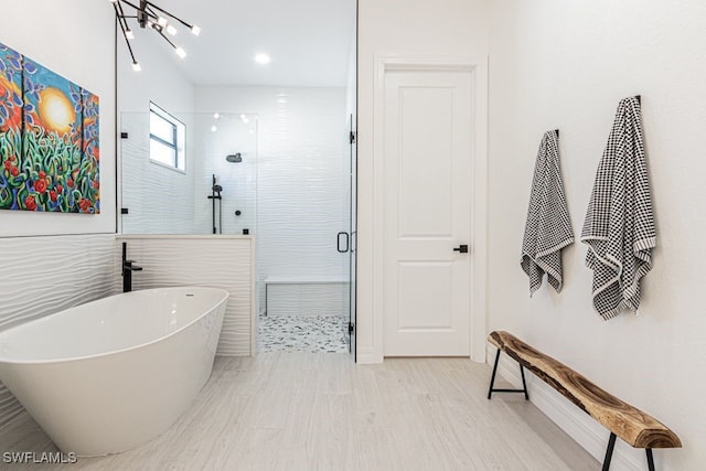 full bathroom with a stall shower, a freestanding tub, and wood finished floors