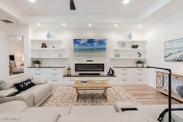 living area featuring recessed lighting, a raised ceiling, visible vents, and light wood-style flooring