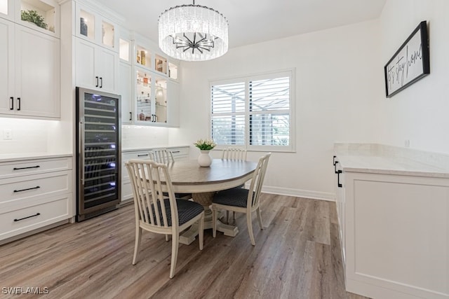 dining area featuring an inviting chandelier, light wood-style flooring, wine cooler, and baseboards