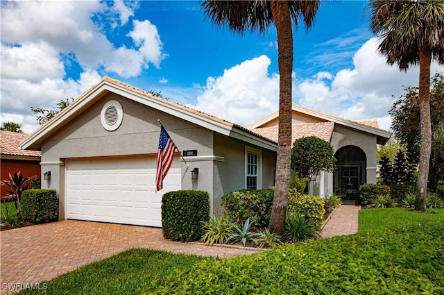 view of front of home with decorative driveway, an attached garage, and stucco siding