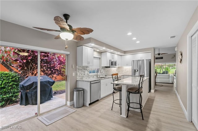 kitchen featuring tasteful backsplash, visible vents, a breakfast bar, stainless steel appliances, and a sink