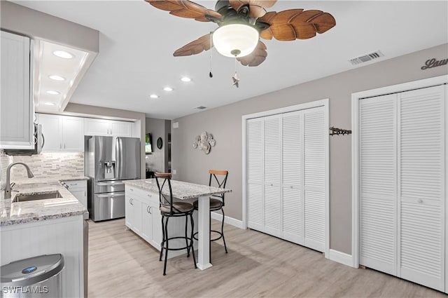 kitchen with a sink, visible vents, a kitchen breakfast bar, appliances with stainless steel finishes, and tasteful backsplash