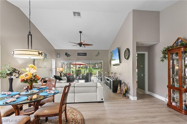 living room featuring visible vents, light wood-style floors, ceiling fan, high vaulted ceiling, and baseboards