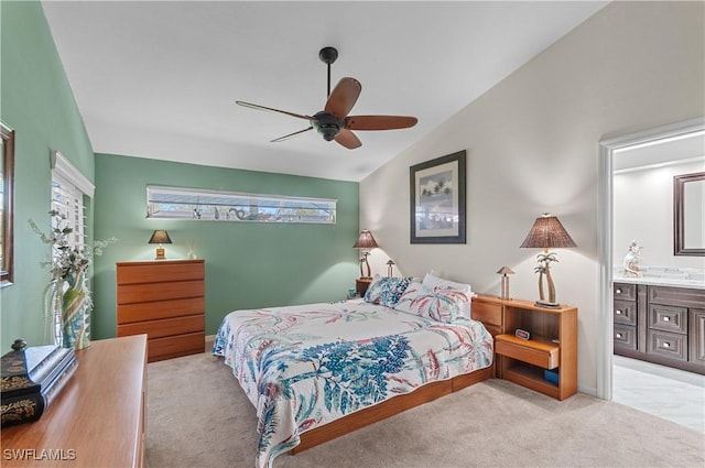 carpeted bedroom featuring vaulted ceiling, ensuite bath, and a ceiling fan