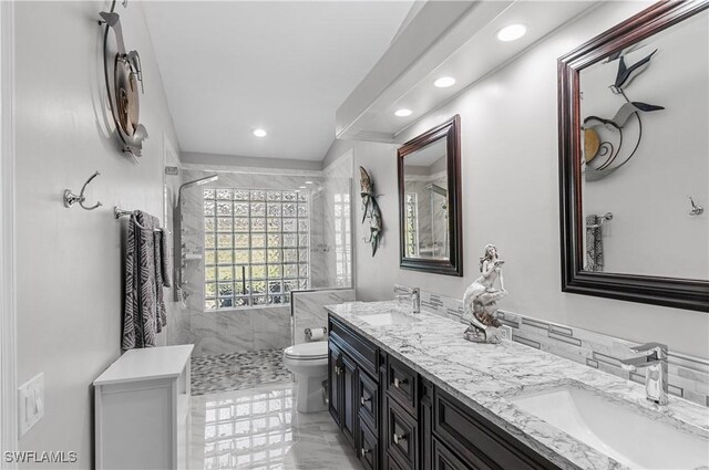 full bathroom with double vanity, a stall shower, a sink, and toilet