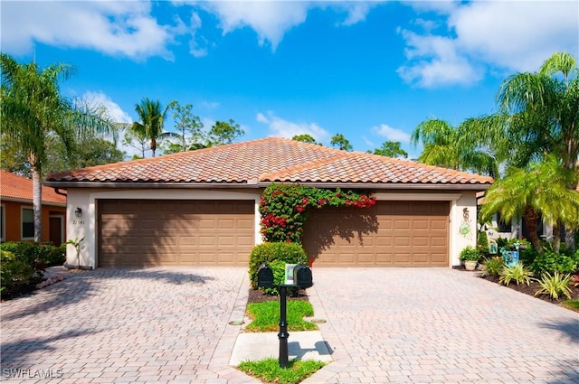 view of front facade with a tiled roof, decorative driveway, an attached garage, and stucco siding