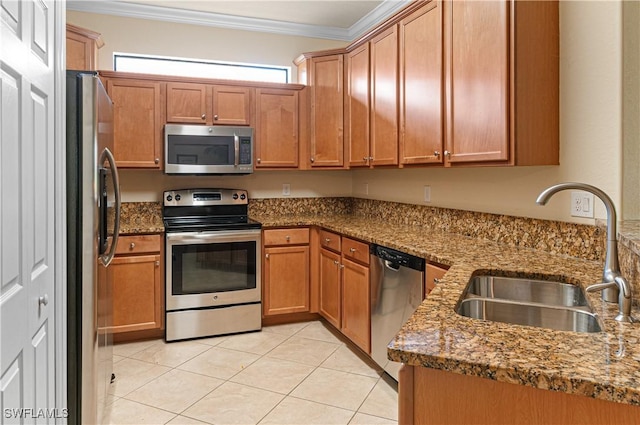 kitchen with stone countertops, light tile patterned flooring, stainless steel appliances, a sink, and ornamental molding