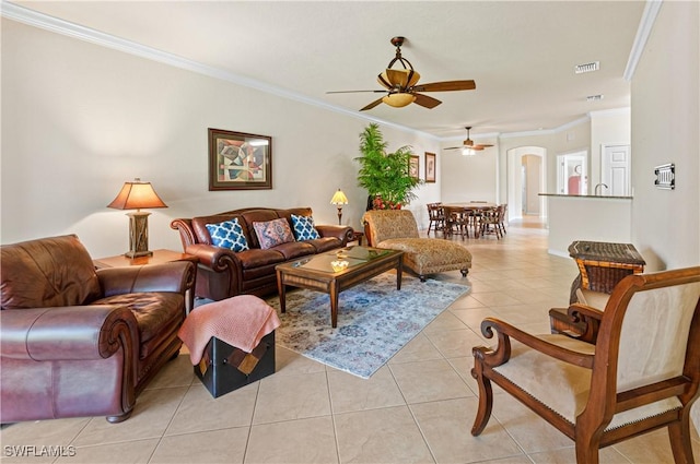 living room with light tile patterned floors, visible vents, ornamental molding, and a ceiling fan