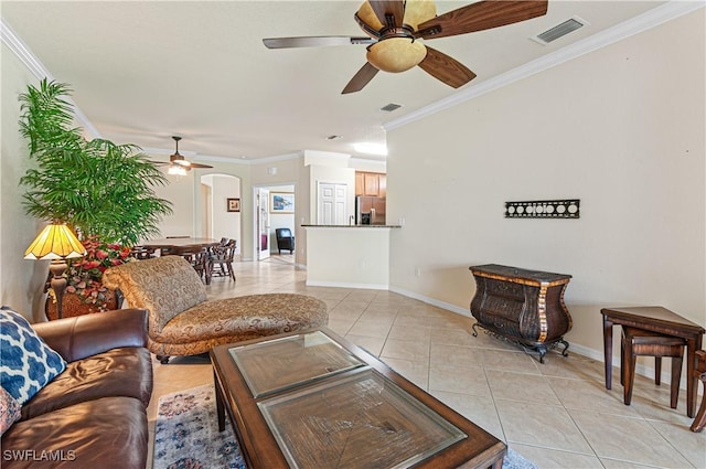 living area with light tile patterned floors, baseboards, visible vents, arched walkways, and crown molding