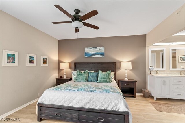 bedroom with light wood-type flooring, ensuite bath, a ceiling fan, and baseboards