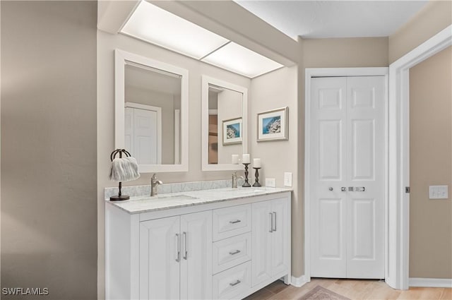 full bathroom featuring double vanity, a closet, a sink, and baseboards