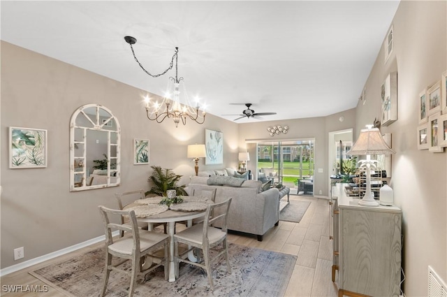 dining area with visible vents, light wood-style flooring, baseboards, and ceiling fan with notable chandelier