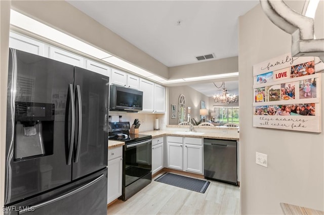 kitchen with light wood-type flooring, white cabinetry, a sink, and black appliances