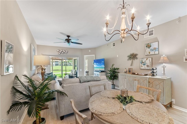 dining space featuring baseboards, visible vents, light wood finished floors, and ceiling fan with notable chandelier