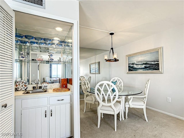 bar with pendant lighting, light colored carpet, visible vents, a sink, and baseboards