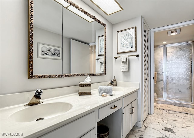 bathroom featuring marble finish floor, double vanity, a stall shower, and a sink