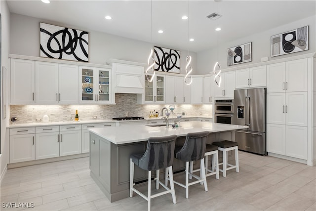 kitchen with a center island with sink, appliances with stainless steel finishes, white cabinets, and a sink