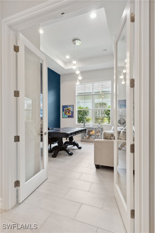 interior space featuring light tile patterned floors, recessed lighting, a tray ceiling, and french doors