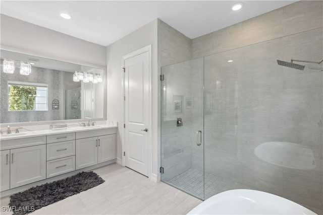 bathroom with a freestanding tub, recessed lighting, a sink, a shower stall, and double vanity