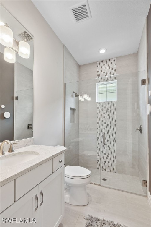 bathroom featuring toilet, a stall shower, vanity, and visible vents