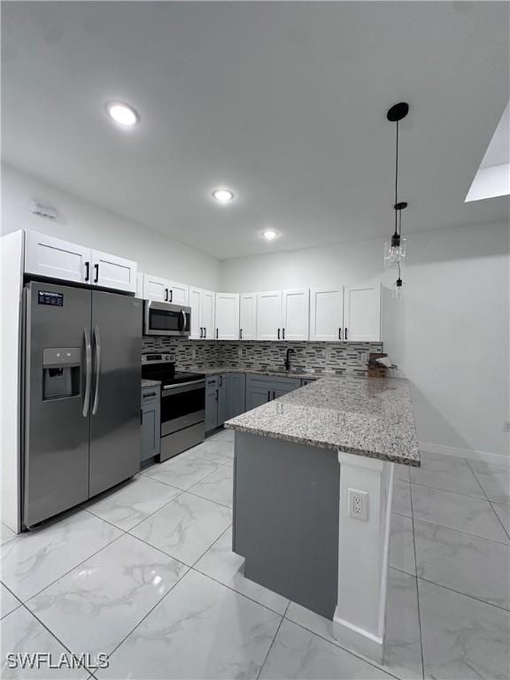 kitchen featuring a peninsula, white cabinetry, marble finish floor, appliances with stainless steel finishes, and light stone countertops