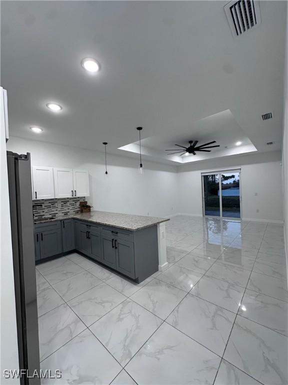 kitchen with a raised ceiling, visible vents, marble finish floor, and open floor plan