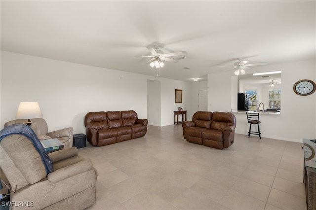 living area with baseboards and a ceiling fan