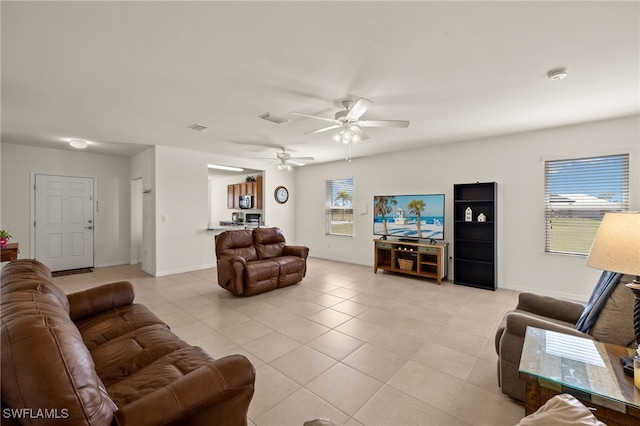 living room featuring a ceiling fan, visible vents, baseboards, and light tile patterned floors